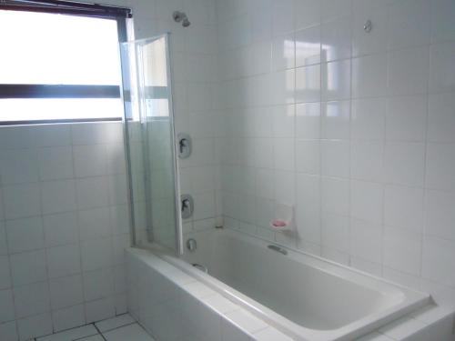 a white bathroom with a tub and a window at Liz' Cottage in Mbabane