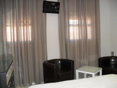 a bedroom with a bed and two chairs and a television at Hotel Lo Monte in Pilar de la Horadada