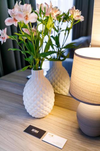 two vases with flowers in them on a table at Hotel Antonio in Uzhhorod
