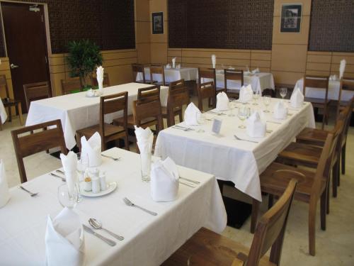 a dining room with white tables and chairs with napkins at Nhi Phi Hotel in Nha Trang