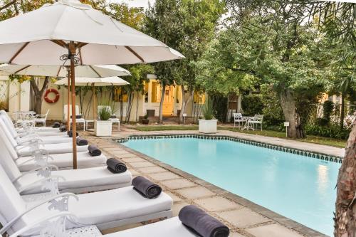 a pool with chaise lounge chairs and an umbrella at Rosenhof Boutique Hotel in Oudtshoorn