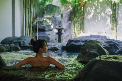 a woman sitting in a bath tub in a waterfall at Serenity Hotel and Spa Kabinburi in Kabin Buri