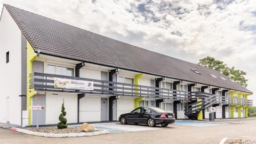 een auto geparkeerd voor een gebouw bij B&B HOTEL Belfort Bessoncourt in Belfort