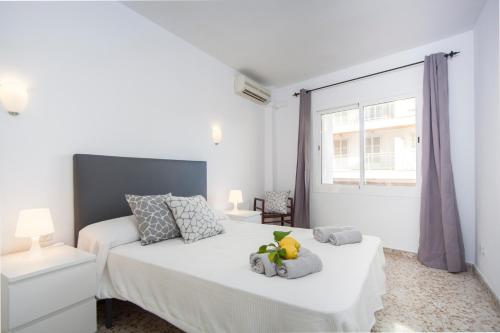 a white bedroom with two beds and a window at Curling in Port d'Alcudia