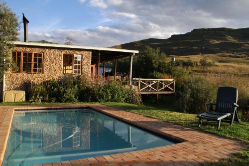 une maison avec une piscine dans la cour dans l'établissement Sani Lodge and Backpackers Sani Pass South Africa, à Col Sani