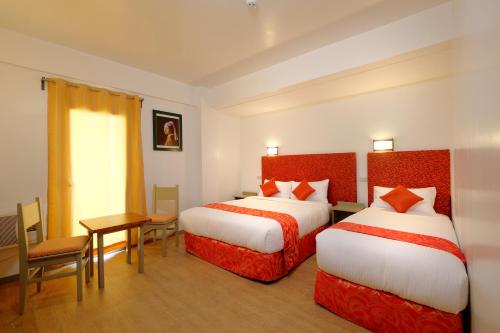 a hotel room with two beds and a table at Frankfurter Deluxe Inn in Cebu City