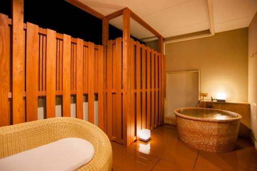 a bathroom with a tub in a room with wooden walls at Isegekusando Iseshinsen in Ise