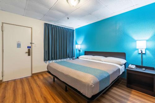 a bedroom with a large bed with a blue wall at Motel 6-Elmsford, NY - White Plains in Elmsford