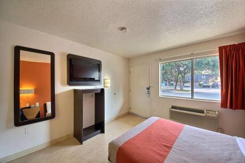a bedroom with a bed and a tv and a window at Motel 6-San Marcos, TX in San Marcos