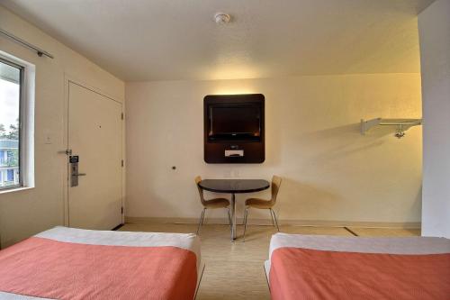 a room with two beds and a table with a tv on the wall at Motel 6-San Marcos, TX in San Marcos