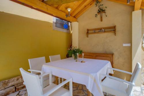 ein Esszimmer mit einem Tisch und weißen Stühlen in der Unterkunft Mediterranes Ferienhaus m. Terrasse in Veli Lošinj