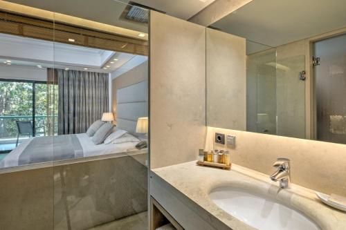 łazienka z umywalką, łóżkiem i lustrem w obiekcie Rodos Park w mieście Rodos