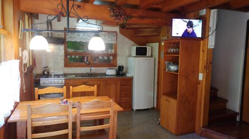 a kitchen with a table and a tv on a wall at Cabañas Temporada in San Martín de los Andes