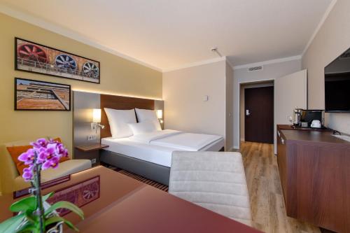 a hotel room with a bed and a living room at Mercure Hotel Duisburg City in Duisburg