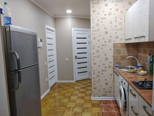 La cuisine est équipée d'un réfrigérateur et d'un évier. dans l'établissement Apartment on Oloy 11, à Tachkent