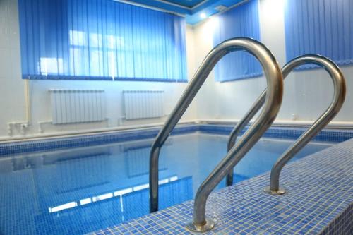 a swimming pool with a metal hand rail next to a swimming pool at Bereke Hotel in Shchūchīnsk