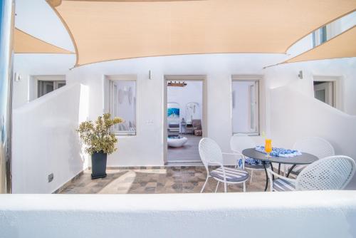 a room with a table and chairs and a bathroom at Angel Luxury Suites in Fira