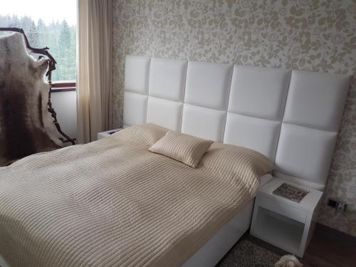 - une chambre avec un lit doté d'une grande tête de lit blanche dans l'établissement Apartment Poiana Brasov, à Poiana Brasov