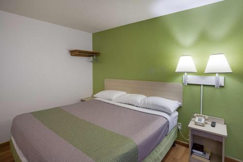 a small room with a bed and a green wall at Motel 6-Binghamton, NY in Binghamton
