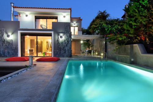 a swimming pool in front of a house at night at Adam & Eve Villas in Sounio