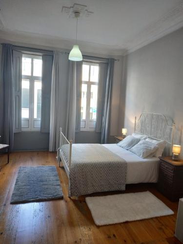 a bedroom with a bed and two windows at Gabriel Guesthouse in Porto