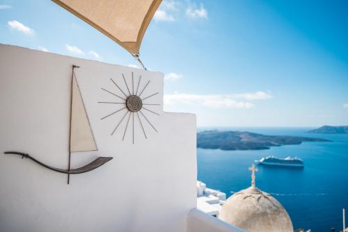 eine Uhr auf der Seite eines Gebäudes mit Meerblick in der Unterkunft Angel Luxury Suites in Fira