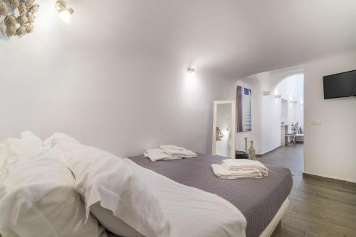 a white bedroom with a bed with towels on it at Angel Luxury Suites in Fira