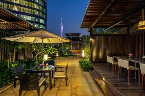 a patio with tables and chairs and an umbrella at Ascott IFC Guangzhou - Free Shuttle Bus For Canton Fair in Guangzhou