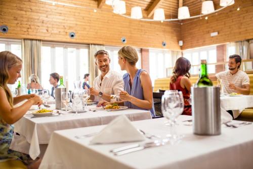 a group of people sitting around a table in a restaurant at ROBINSON QUINTA DA RIA - All Inclusive in Vila Nova de Cacela