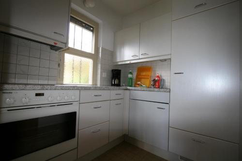 a white kitchen with white cabinets and a window at Residenza Paradiso di Vacanze in Locarno