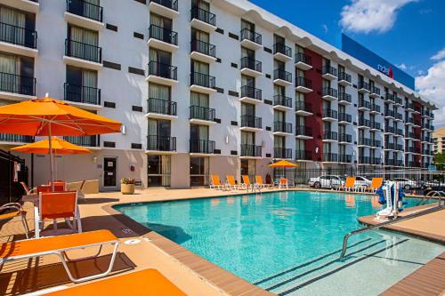 uma piscina do hotel com cadeiras e guarda-sóis em frente a um hotel em Motel 6-Atlanta, GA - Atlanta Airport em Atlanta