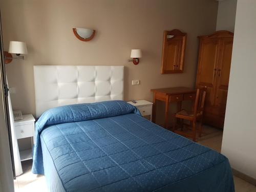 a bedroom with a blue bed with a white headboard at Hostal Centro in Toledo