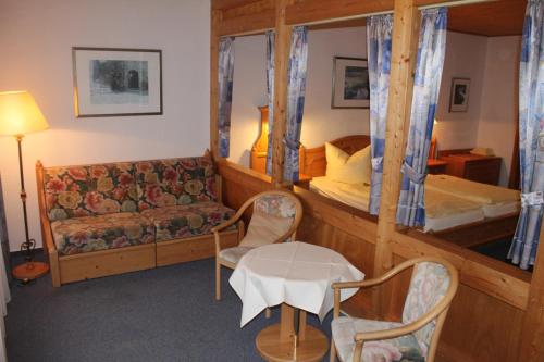 a bedroom with a bunk bed and a couch and a table at Waldhotel Dornröschenshöh in Hemfurth-Edersee