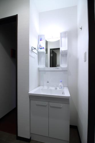 a white bathroom with a sink and a mirror at W&M House in Kanazawa