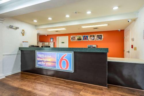 a lobby with a welcome sign and an orange wall at Motel 6-Shreveport, LA in Shreveport
