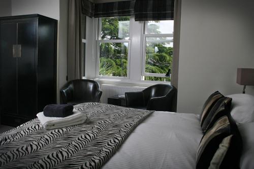 a bedroom with a bed with chairs and a window at TOWNHOUSE ROOMS in Truro