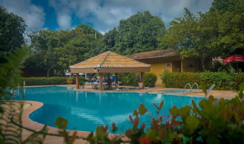 uma piscina com um gazebo ao lado de uma casa em Pousada do Forte em Barra do Cunhau