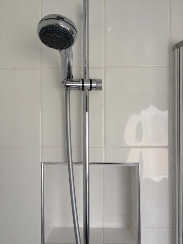 a shower with a chrome shower head in a bathroom at TOWNHOUSE ROOMS in Truro