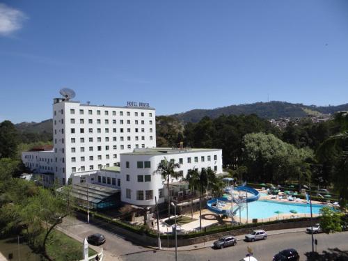 a hotel with a swimming pool in front of two buildings at Hotel Brasil in São Lourenço