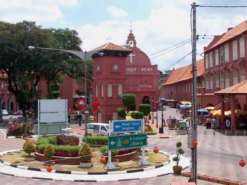 a street with a red building with a clock tower at Cozy Riverside Hotel in Melaka