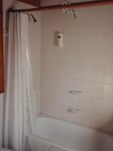a bathroom with a bath tub with a shower curtain at Cabañas Temporada in San Martín de los Andes