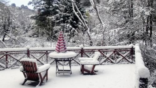 two chairs and a table covered in snow at Cabañas Temporada in San Martín de los Andes