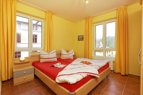 a bedroom with a large bed with two windows at Haus Grete Wohnung 13 in Ostseebad Koserow
