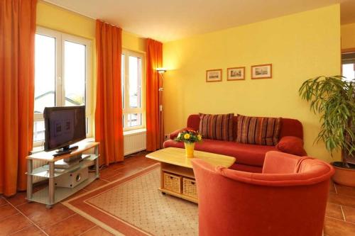 a living room with a red couch and a tv at Haus Grete Wohnung 14 in Ostseebad Koserow