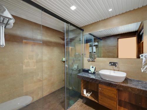 y baño con lavabo y ducha acristalada. en The Fern Residency, Bhuj en Bhuj