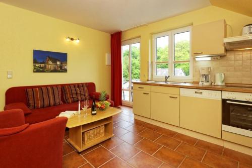 a living room with a red couch and a kitchen at Haus Grete Wohnung 15 in Ostseebad Koserow