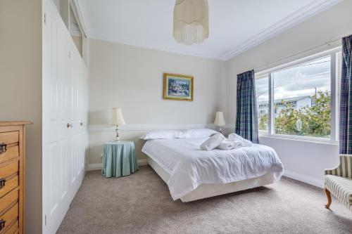 a white bedroom with a bed and a window at Serpentine Rose in Albany