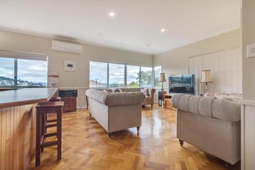 a living room with couches and a kitchen with windows at Serpentine Rose in Albany