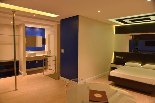 a bedroom with a bed and a table and a bathroom at Villages Motel by Drops in Lages
