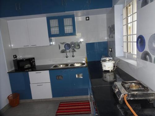a kitchen with blue and white cabinets and a sink at Haritham in Tiruchchirāppalli